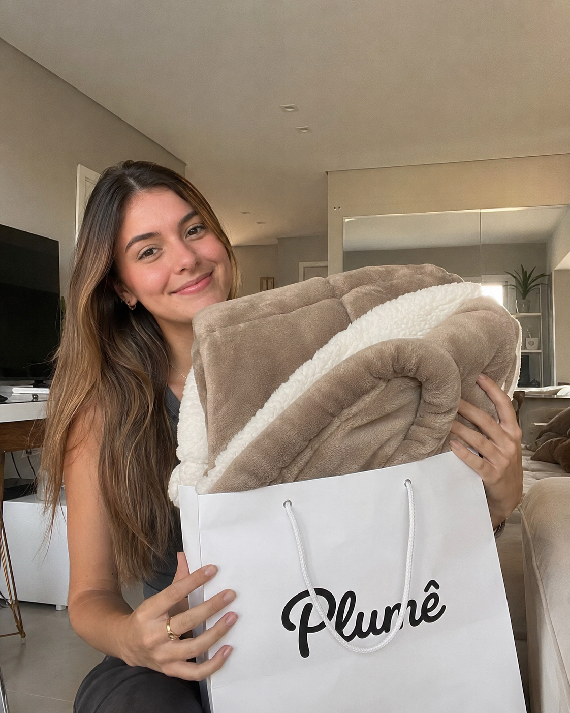Cliente mostrando cobertor Plumê bege em casa